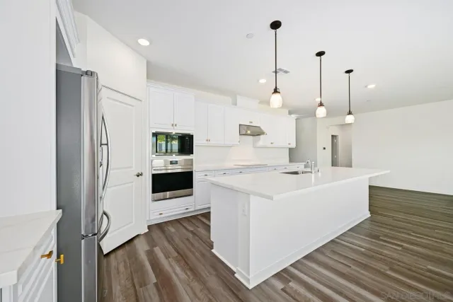 a large white kitchen with lots of counter top space a sink a refrigerator and window
