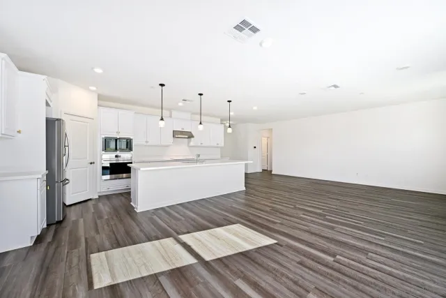 a large white kitchen with lots of counter top space a sink a refrigerator and window