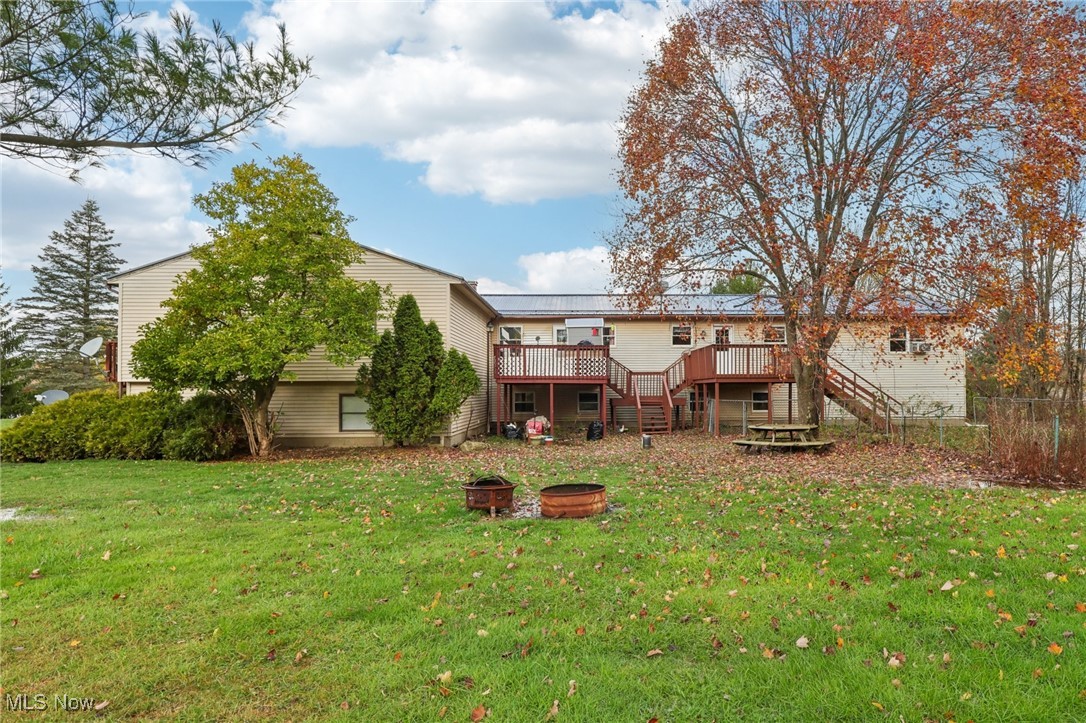 6370 Trumbull Road Geneva, OH 44041 - Photo 41 of 50 Rear view of house with stairway, a deck, a lawn, and a fire pit