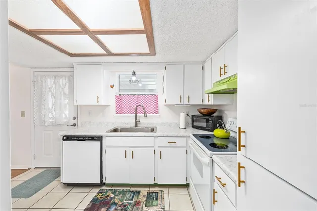 a kitchen with a sink a stove cabinets and wooden floor