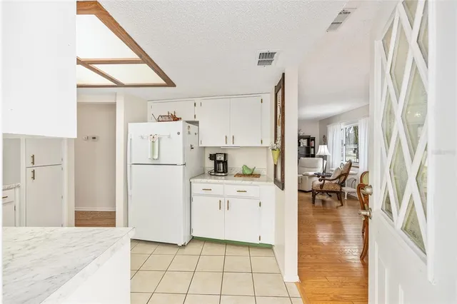 a kitchen with white cabinets and refrigerator