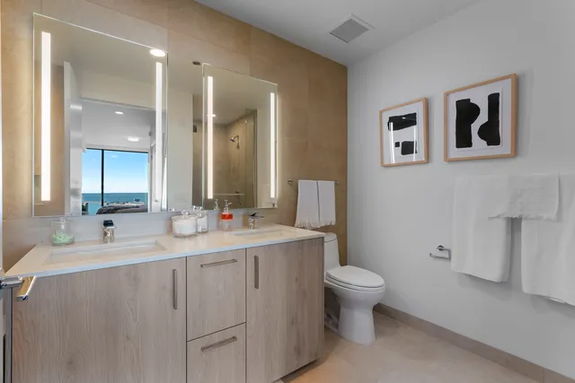a bathroom with a double vanity sink toilet and mirror