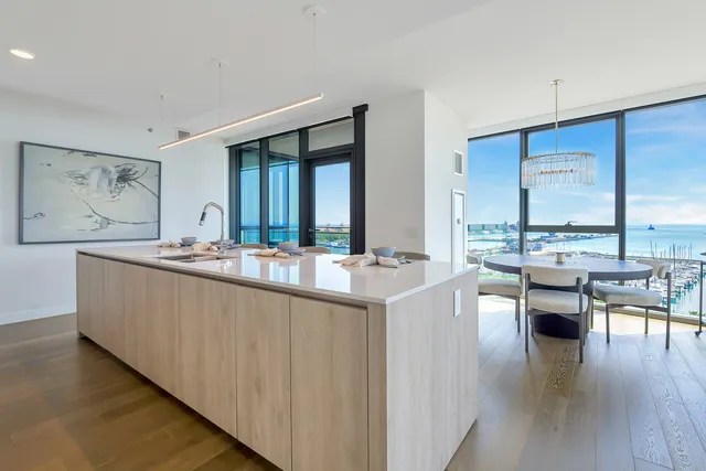a living room with stainless steel appliances granite countertop furniture a large window and a kitchen view