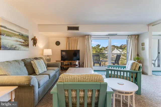 a living room with furniture a flat screen tv and a refrigerator