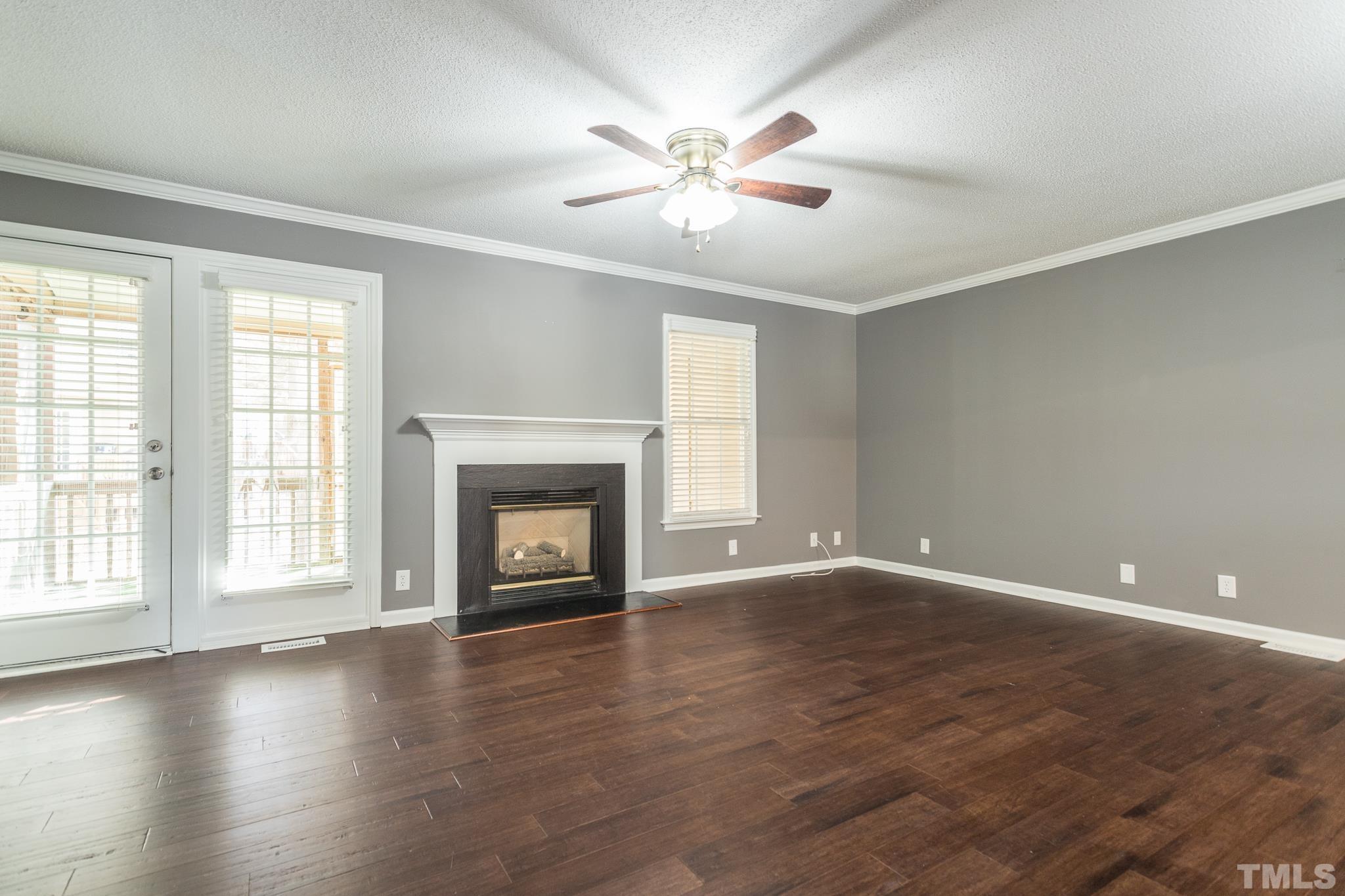 4428 Antique Lane Raleigh, NC 27616 - Photo 16 of 30 an empty room with wooden floor fireplace and windows