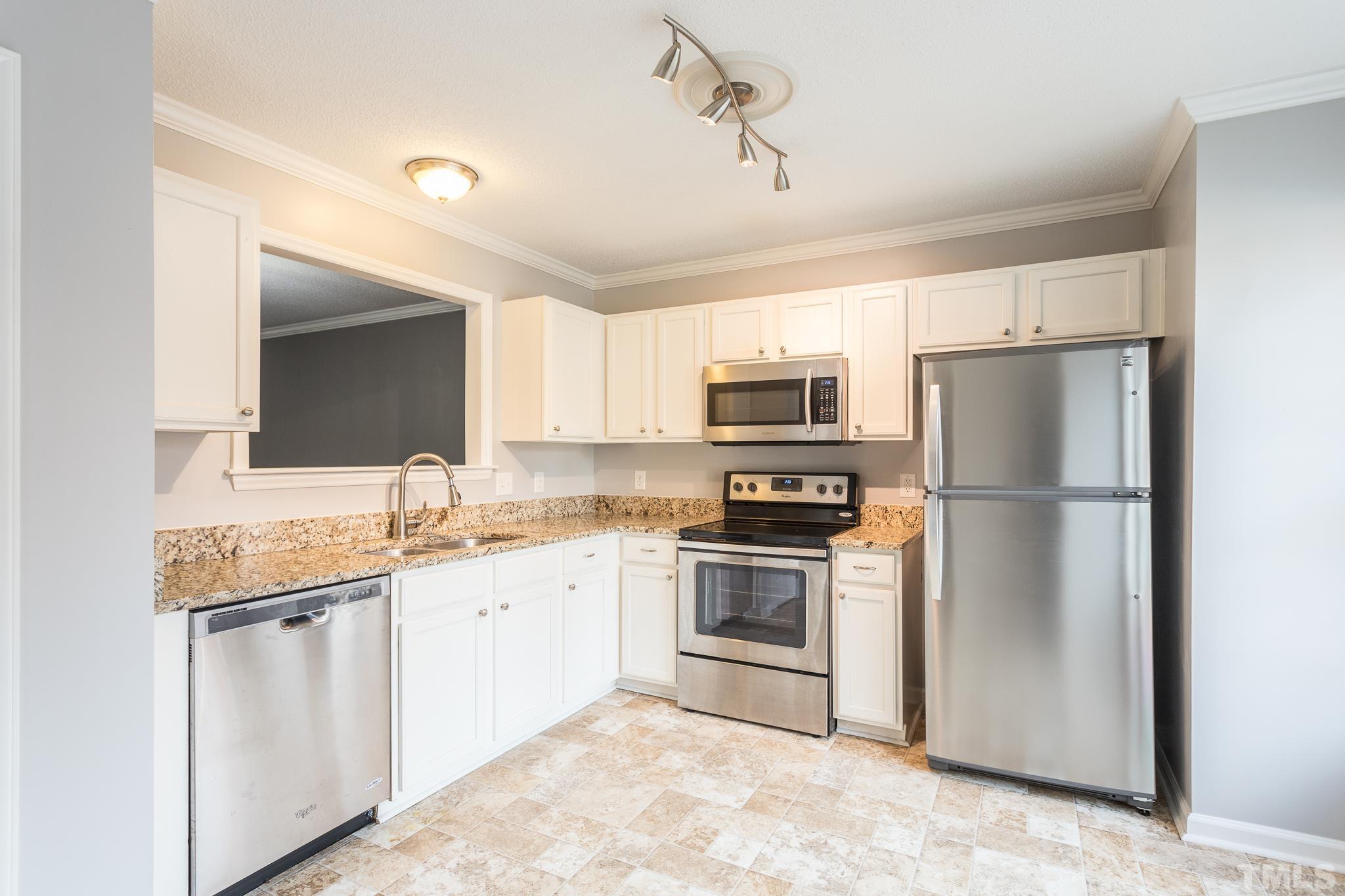4428 Antique Lane Raleigh, NC 27616 - Photo 7 of 30 a kitchen with a sink white cabinets and stainless steel appliances