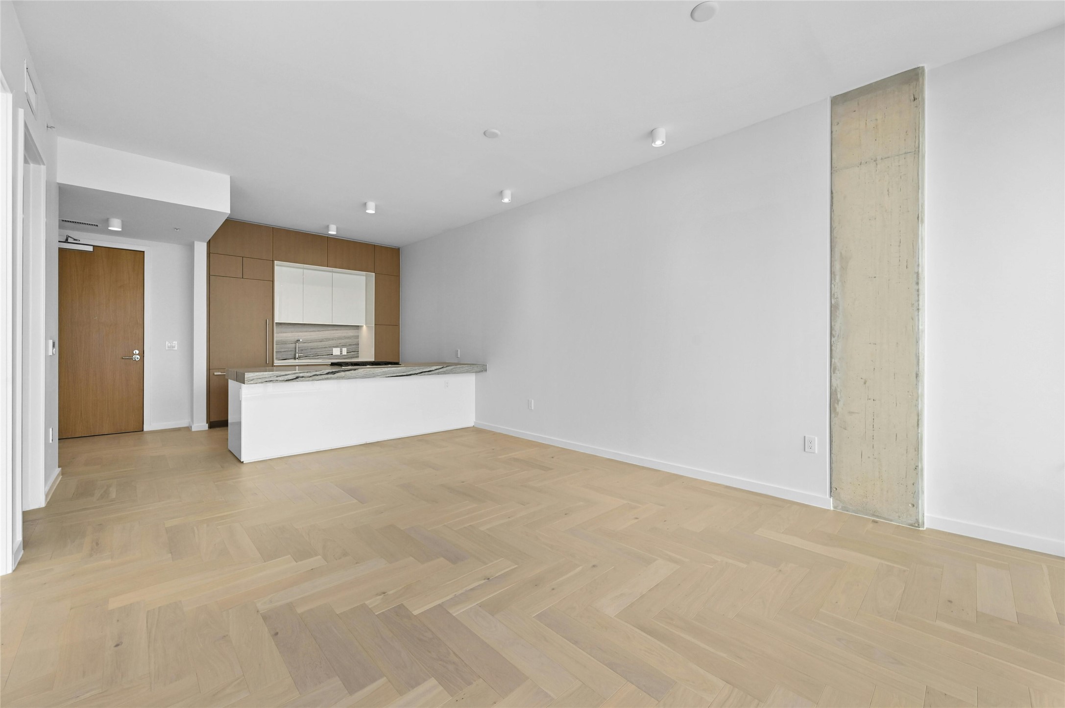 313 West 17th Street, Unit 1702 Austin, TX 78701 - Photo 33 of 34 Residence 1702 showcases the A2 floorplan with open living and dining framed by herringbone oak floors and clean architectural lines. The modern kitchen features a waterfall island with stone counters, custom cabinetry, and integrated Bosch® appliances.