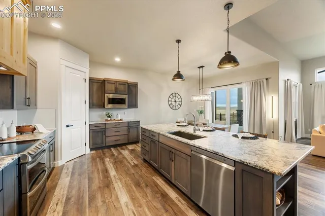 a kitchen with stainless steel appliances granite countertop a sink a stove and a wooden floors