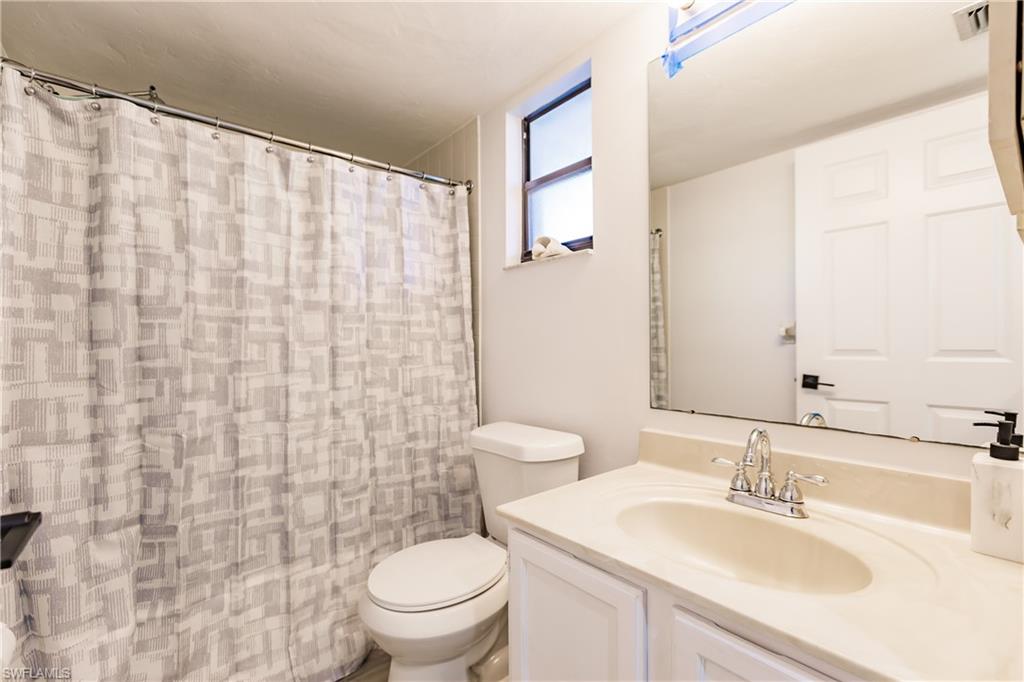 600 Neapolitan Way, Unit 152 Naples, FL 34103 - Photo 16 of 41 a bathroom with a sink a toilet and a mirror