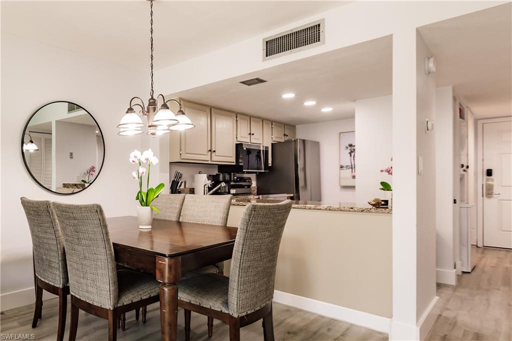 600 Neapolitan Way, Unit 152 Naples, FL 34103 - Photo 3 of 41 a dining room with furniture a chandelier and wooden floor