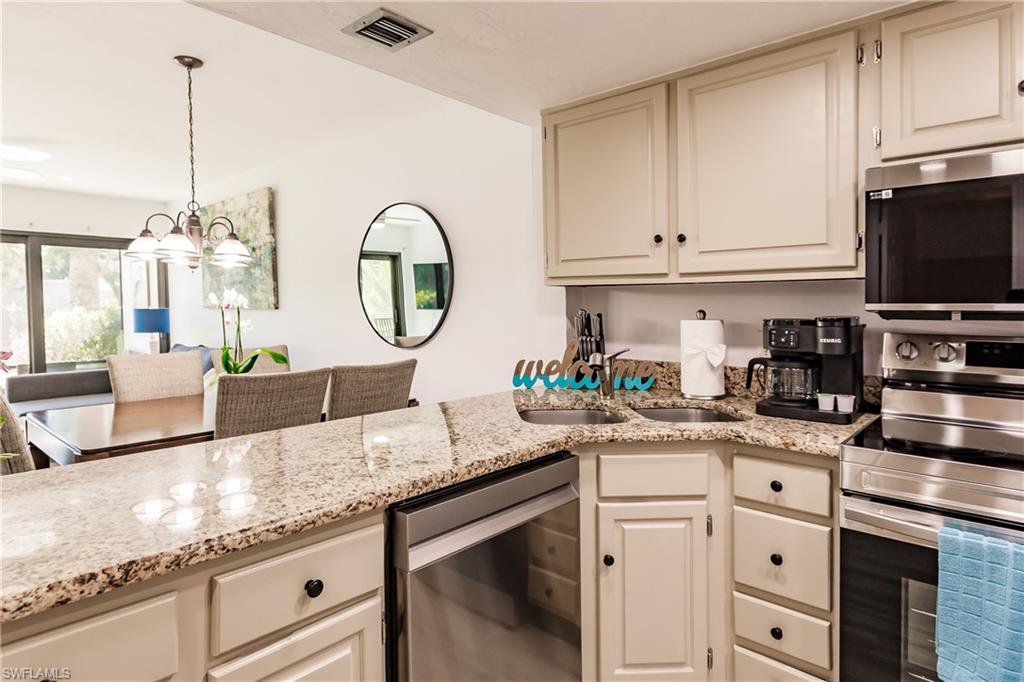 600 Neapolitan Way, Unit 152 Naples, FL 34103 - Photo 5 of 41 a kitchen with granite countertop a sink stainless steel appliances and cabinets