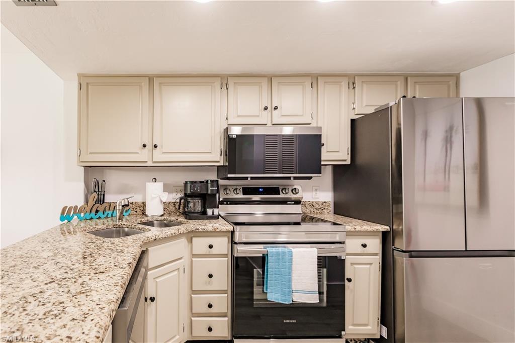 600 Neapolitan Way, Unit 152 Naples, FL 34103 - Photo 6 of 41 a kitchen with stainless steel appliances a stove microwave and refrigerator