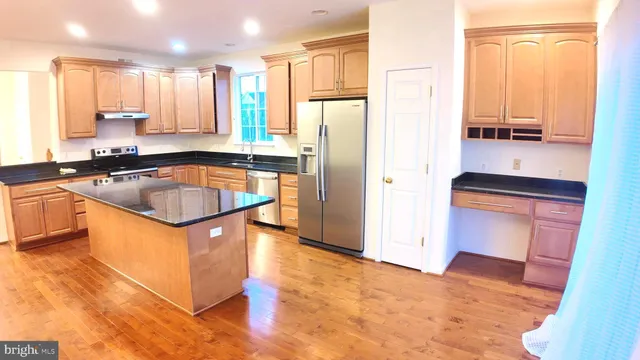 a kitchen with stainless steel appliances granite countertop a sink a stove and a refrigerator