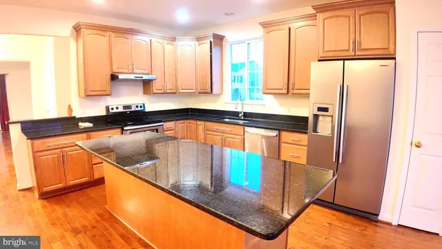 a kitchen with stainless steel appliances granite countertop a sink a stove and a refrigerator