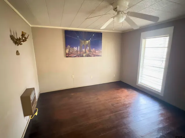 an empty room with wooden floor ceiling fan and windows