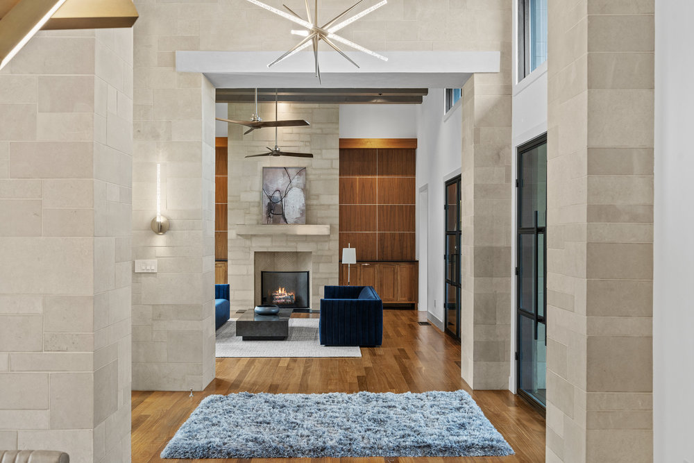 1905 Paisano Road Austin, TX 78746 - Photo 14 of 40 Hardwood floors lead to a sun-drenched living area featuring a stone fireplace and elegant built-in cabinetry.
