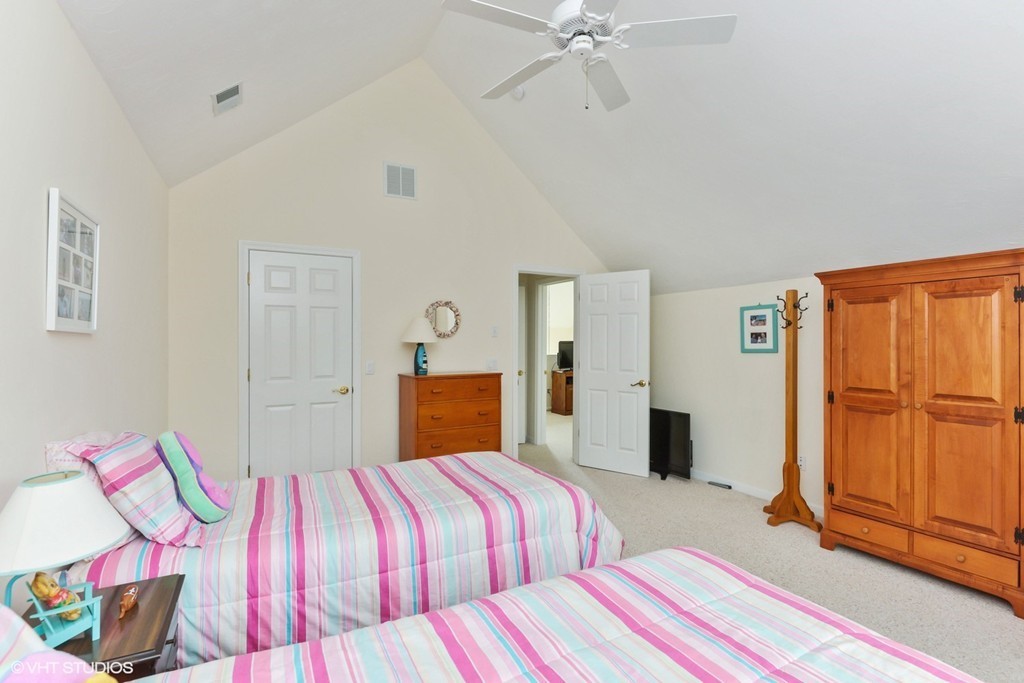23 Gold Leaf Lane, Unit 23 Mashpee, MA 02649 - Photo 14 of 15 a bedroom with a bed and dresser with mirror