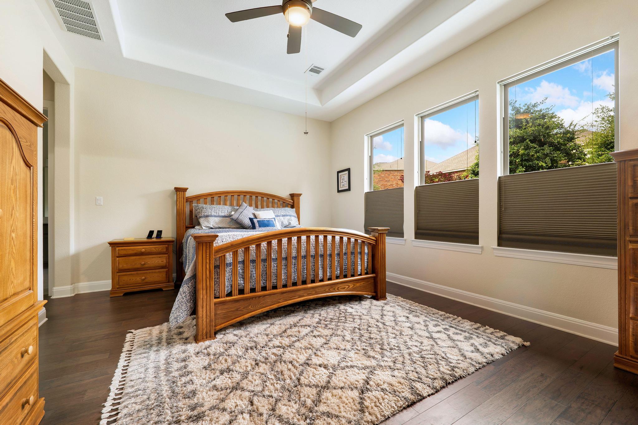 1009 Legacy Crossing Georgetown, TX 78628 - Photo 27 of 40 A well-lit bedroom with dark wood flooring and a classic wooden bed frame, complemented by a large area rug.