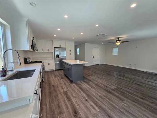 a large kitchen with kitchen island a large counter space a sink a window and stainless steel appliances