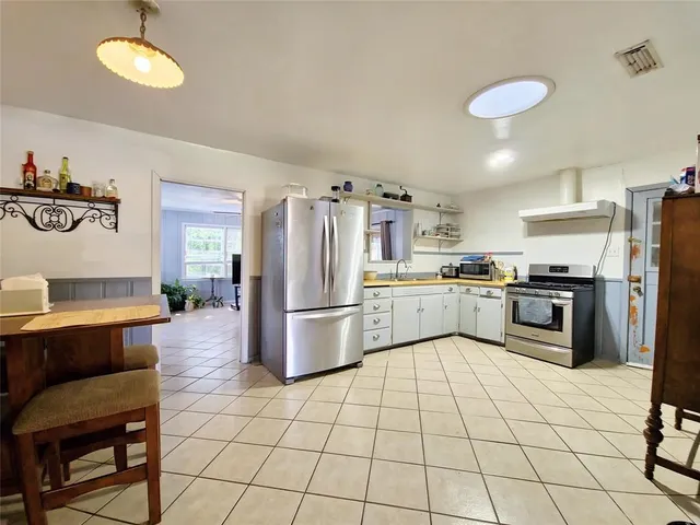 a kitchen with a refrigerator a sink dishwasher a stove and white cabinets with wooden floor