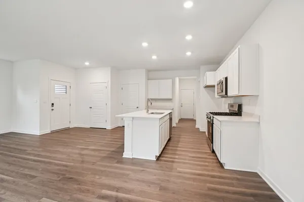 a large kitchen with kitchen island a sink stainless steel appliances and white cabinets