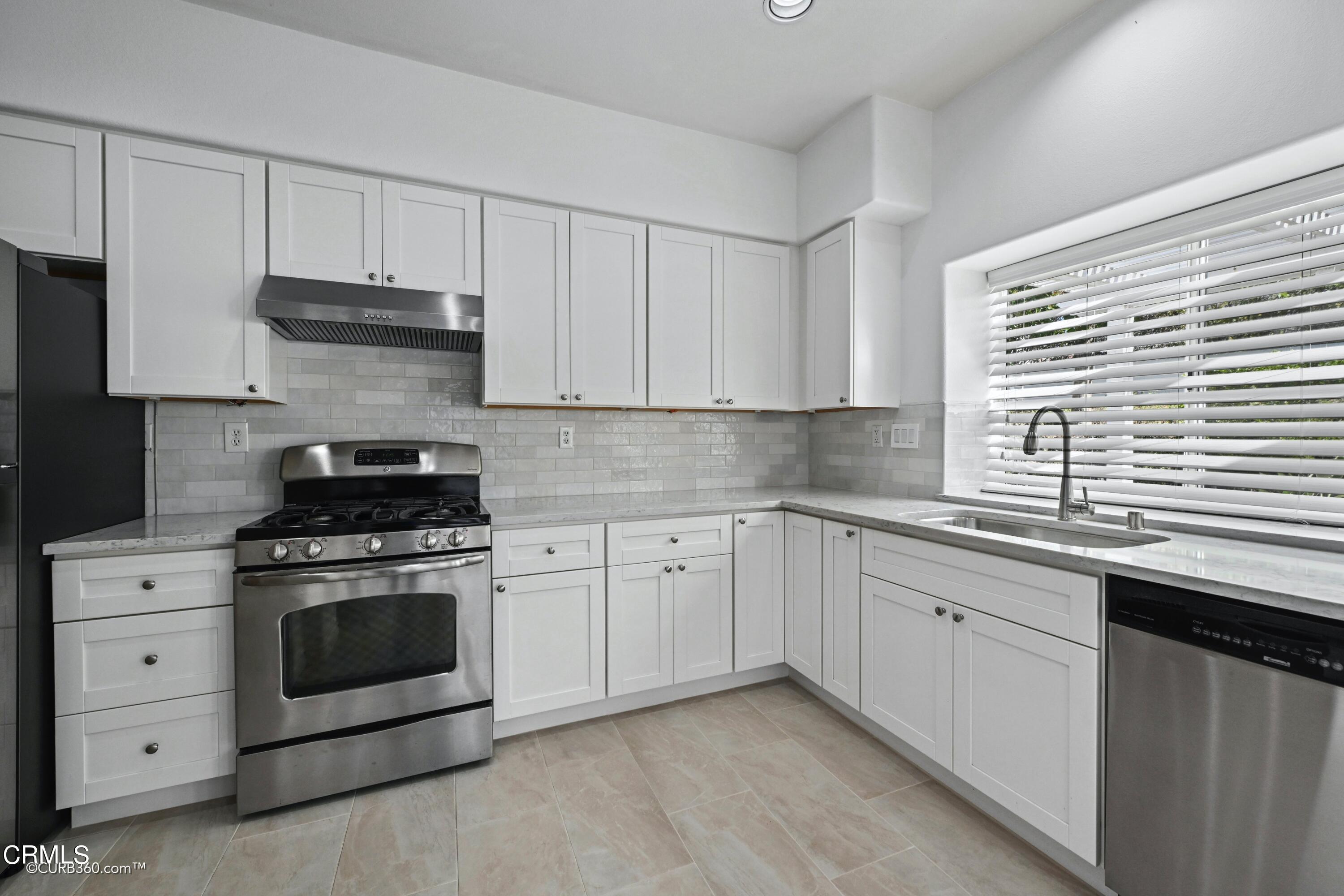 4947 Tilos Way Oceanside, CA 92056 - Photo 10 of 37 a kitchen with granite countertop white cabinets and white stainless steel appliances