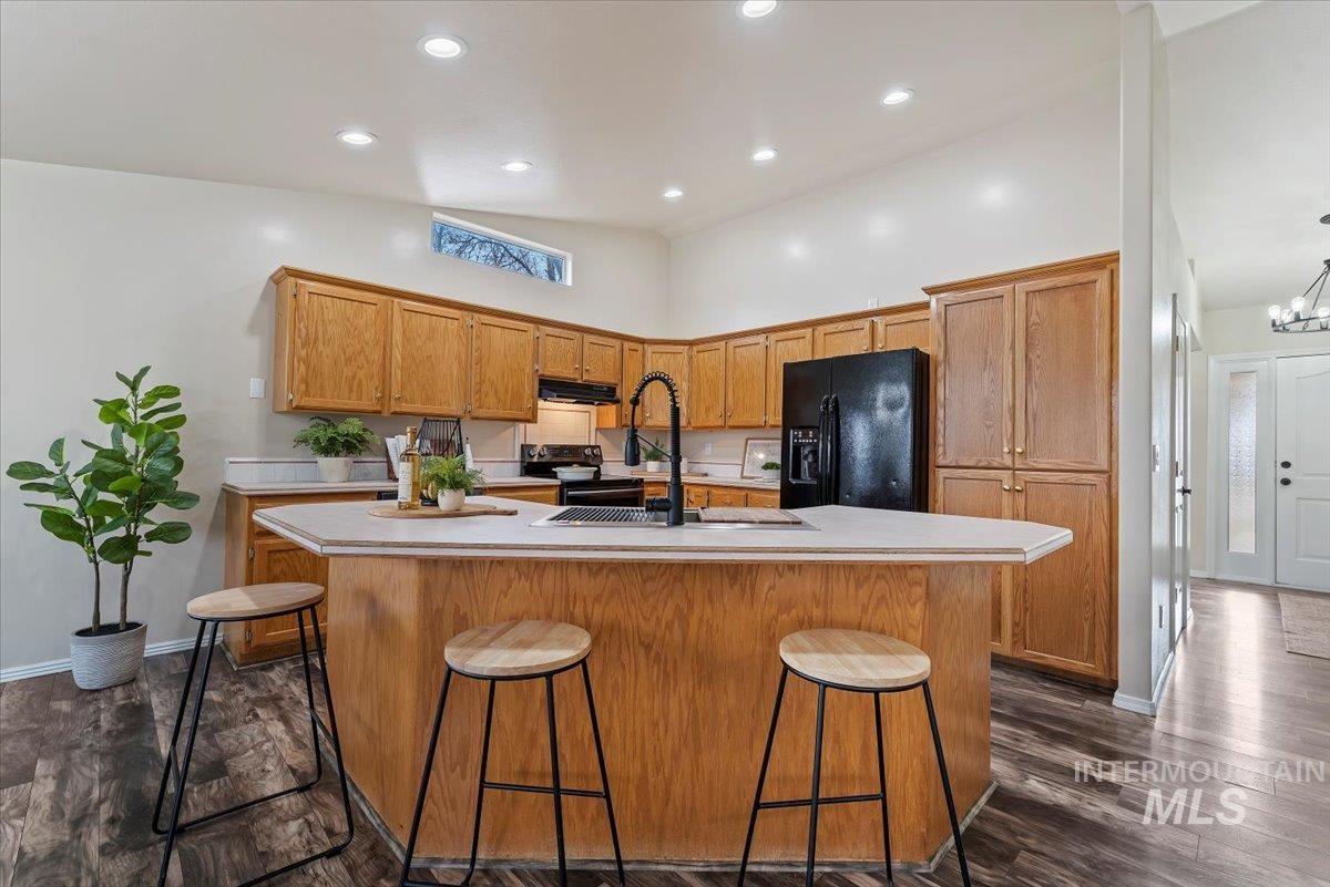 1528 East Peridot Street Meridian, ID 83646 - Photo 14 of 28 Kitchen featuring brown cabinetry, light countertops, a kitchen bar, black appliances, and a center island with sink