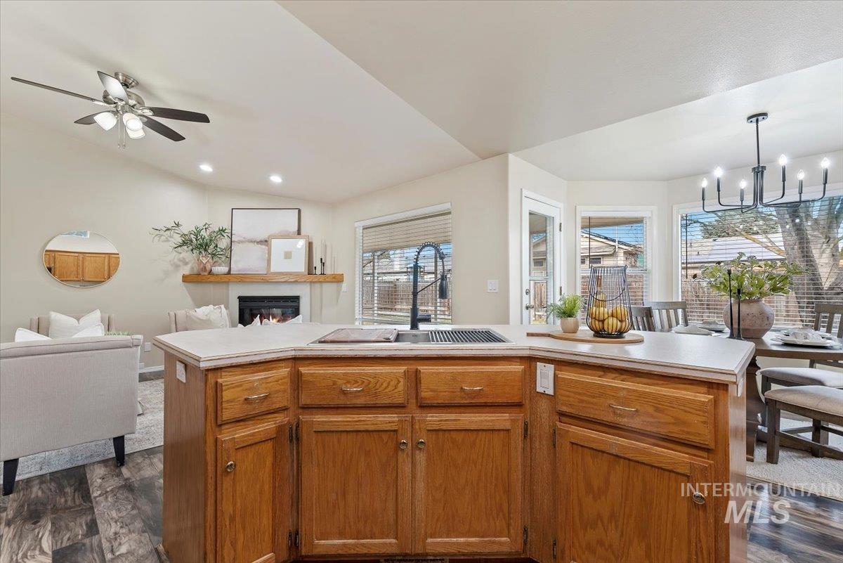1528 East Peridot Street Meridian, ID 83646 - Photo 28 of 28 Kitchen with open floor plan, light countertops, a glass covered fireplace, brown cabinets, and an island with sink