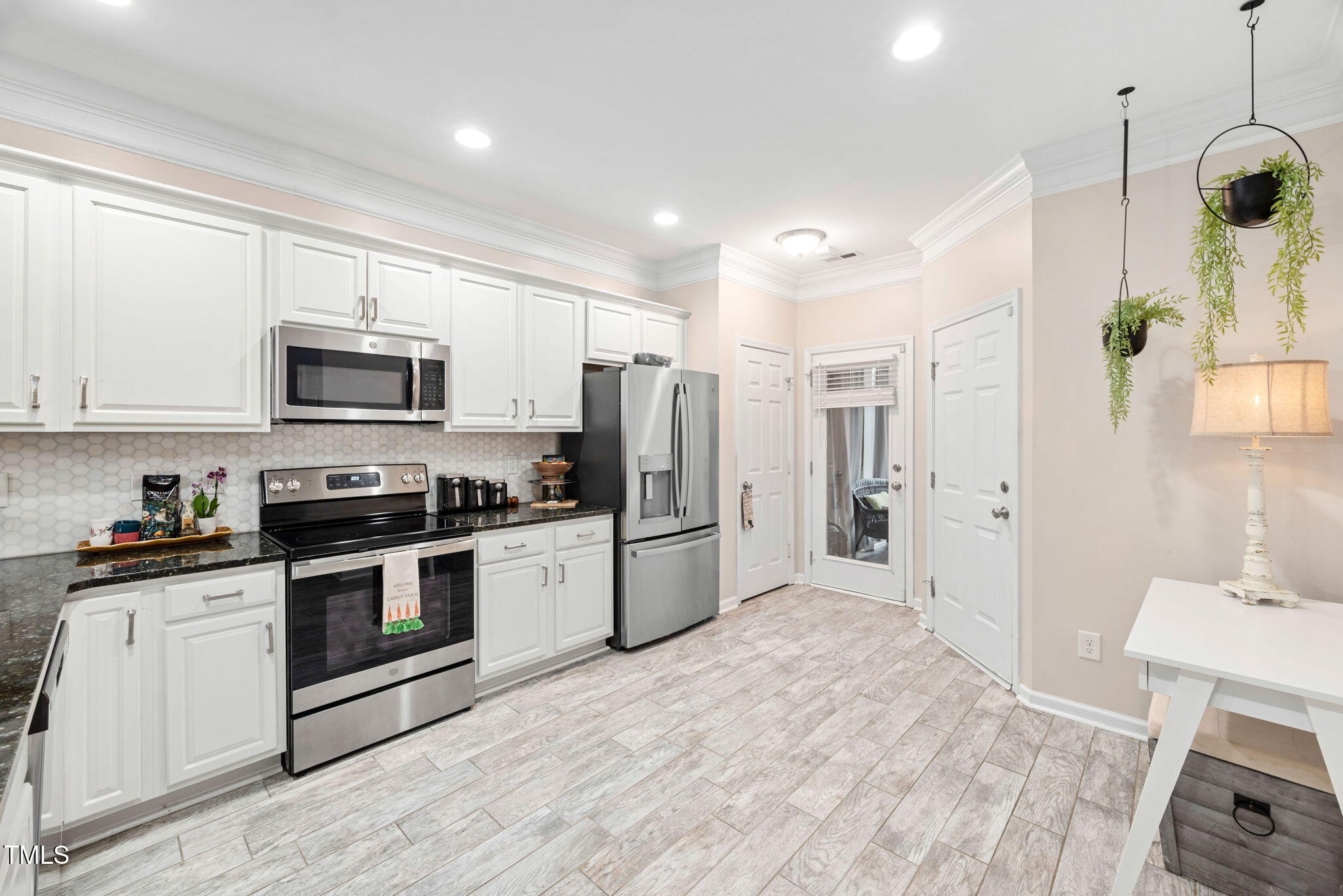 992 Ambergate Apex, NC 27502 - Photo 11 of 39 a kitchen with stainless steel appliances granite countertop a refrigerator a stove a sink a microwave oven with white cabinets and wooden floor