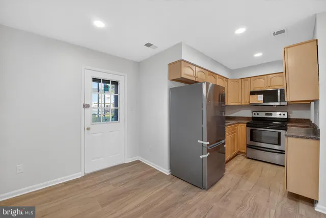 a kitchen with granite countertop a refrigerator and a stove top oven
