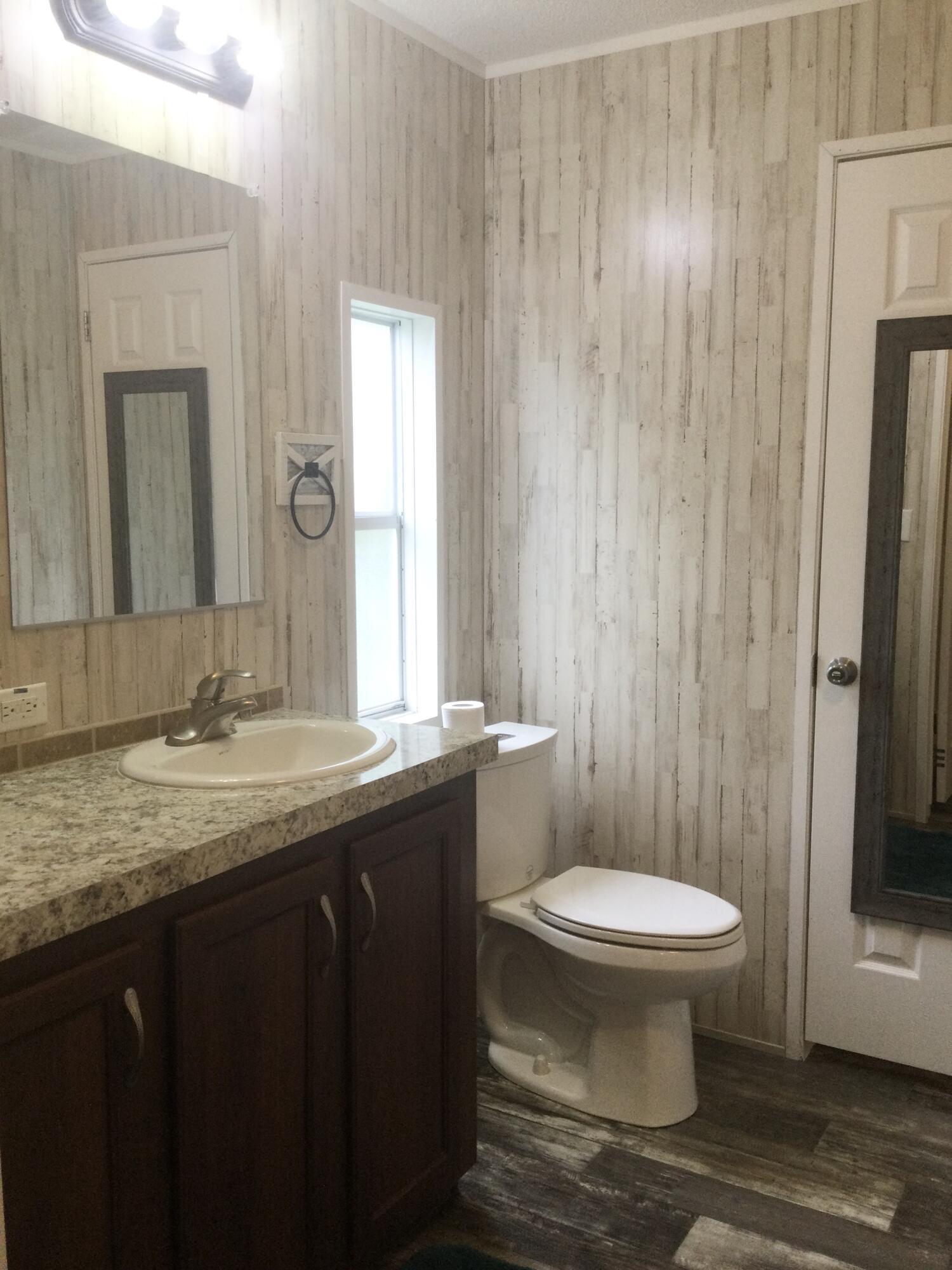 5000 Southeast Federal Highway, Unit 82 Stuart, FL 34997 - Photo 14 of 22 a bathroom with a granite countertop toilet a sink and a mirror