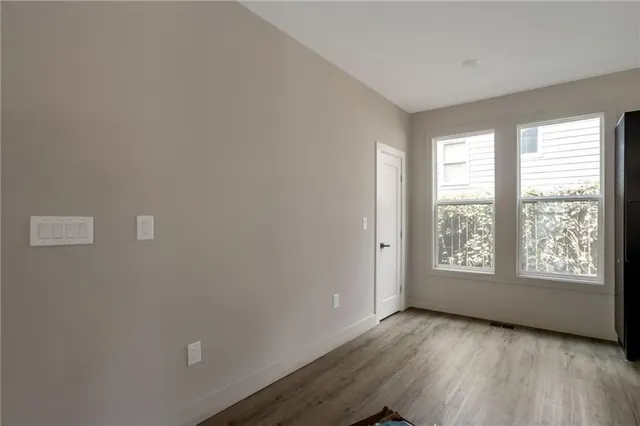 a view of an empty room with a window and wooden floor