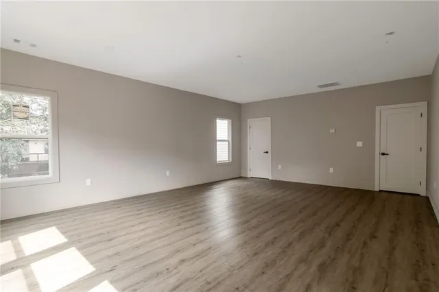an empty room with wooden floor and windows