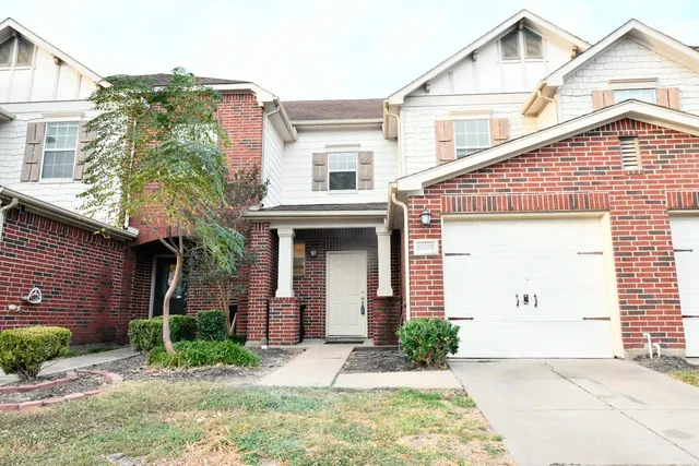 a view of a white house with large windows and plants