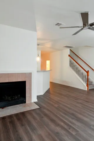 a view of an empty room with wooden floor fireplace and a window