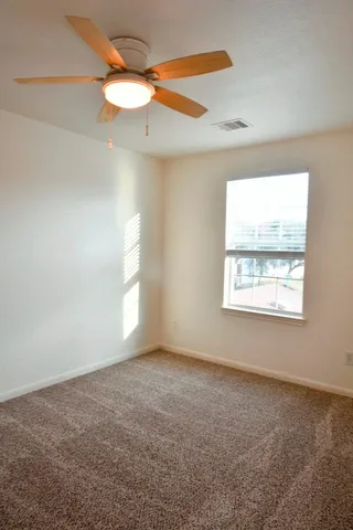 an empty room with a ceiling fan and wooden floor
