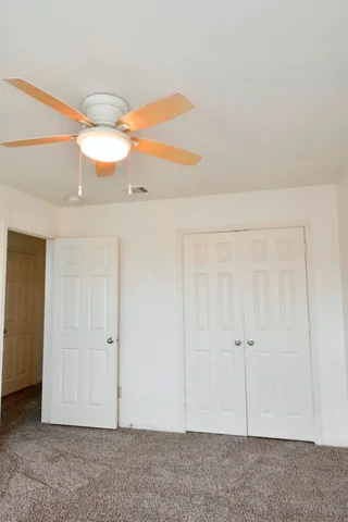 an empty room with a ceiling fan and a window
