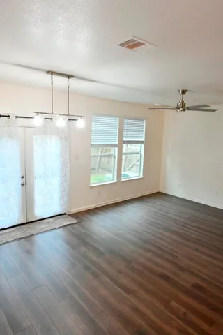 an empty room with wooden floor closet and windows