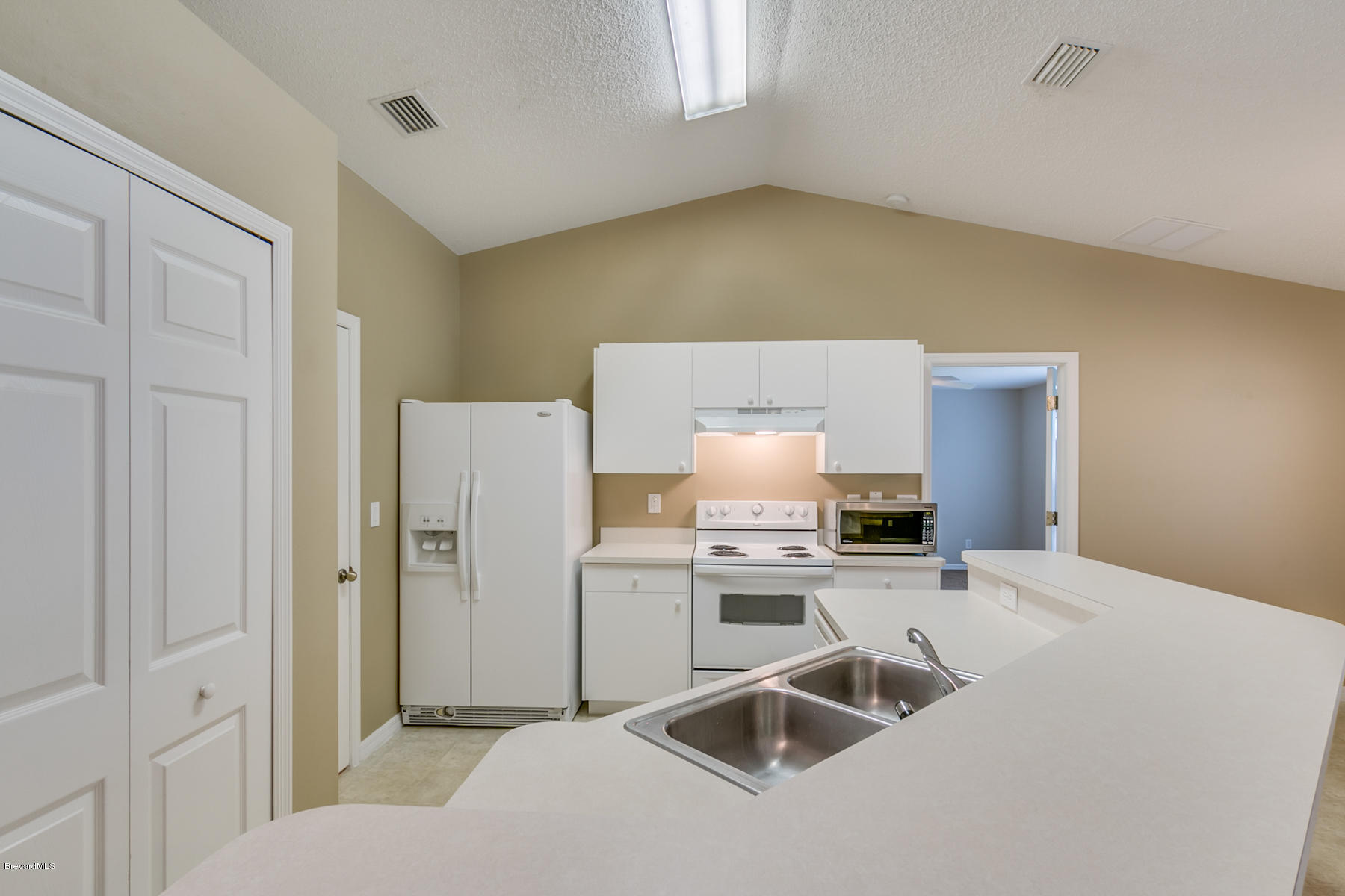 1304 Rabbit Street Southeast Palm Bay, FL 32909 - Photo 3 of 37 a kitchen with stainless steel appliances a sink a stove a refrigerator a washer and dryer