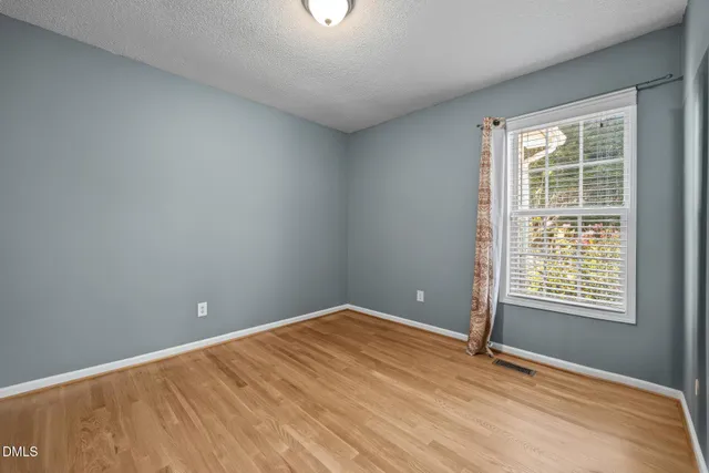 a view of an empty room with wooden floor a ceiling fan and a fireplace