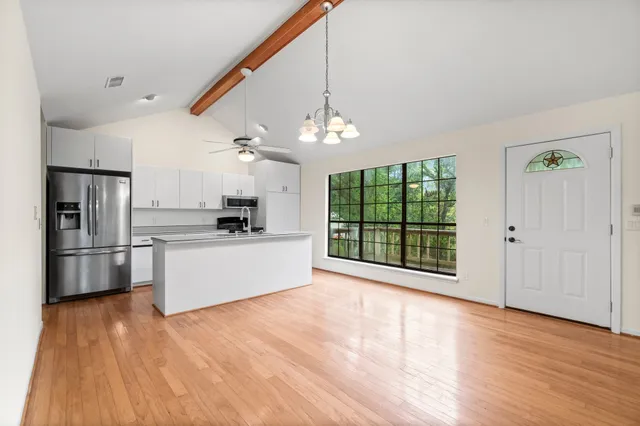 a kitchen with stainless steel appliances a stove top oven a refrigerator a sink and dishwasher with wooden floor