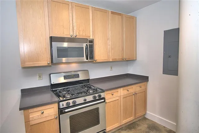 a kitchen with granite countertop a stove top oven microwave and cabinets