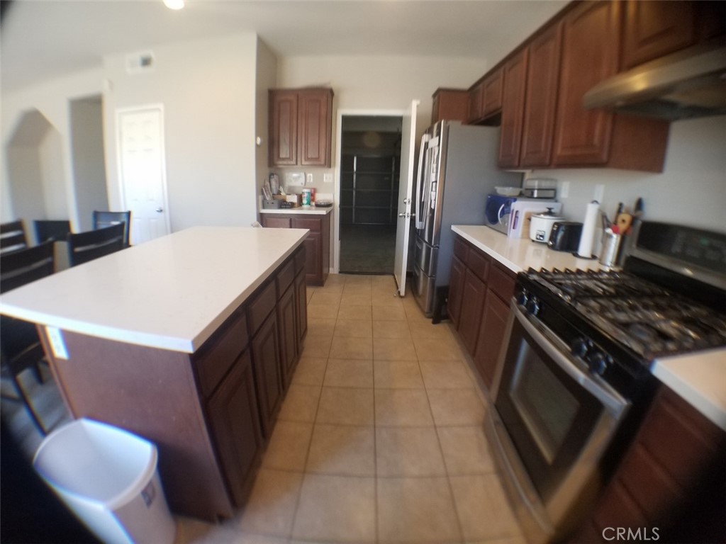1688 Julia Way Riverside, CA 92501 - Photo 26 of 36 a kitchen with stainless steel appliances a stove a refrigerator a sink a dining table and chairs