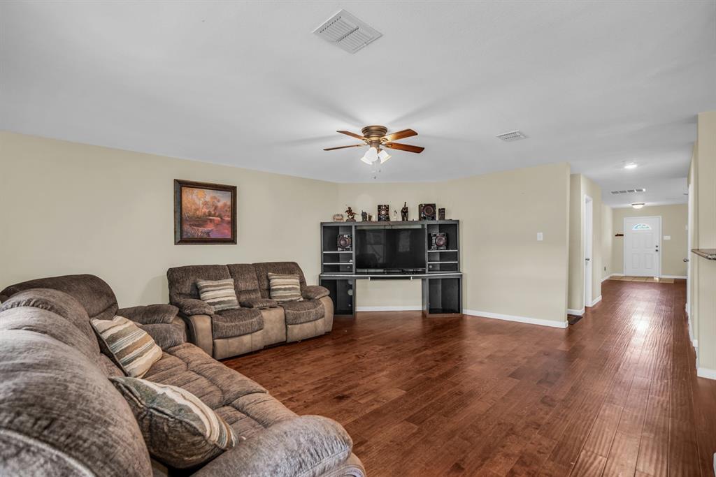 5718 Green Ivy Road Denton, TX 76210 - Photo 12 of 37 Spacious living area featuring rich wood-finish flooring, a ceiling fan with integrated lighting, and neutral wall tones