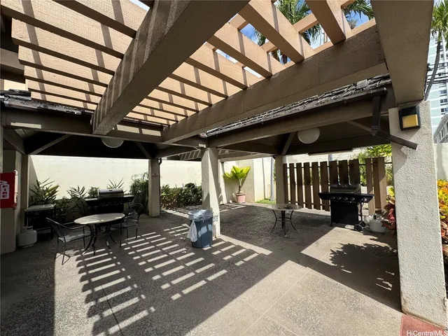 a view of a patio with table and chairs a barbeque with wooden floor and roof