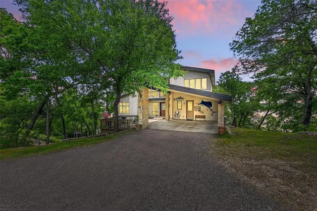 a view of a brick house next to a yard with big trees