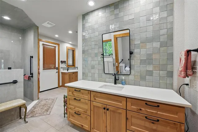 a spacious bathroom with a granite countertop sink a mirror and shower
