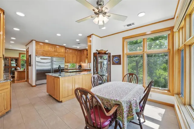 a kitchen with stainless steel appliances kitchen island granite countertop a refrigerator a stove a sink dishwasher with a dining table and chairs with wooden floor