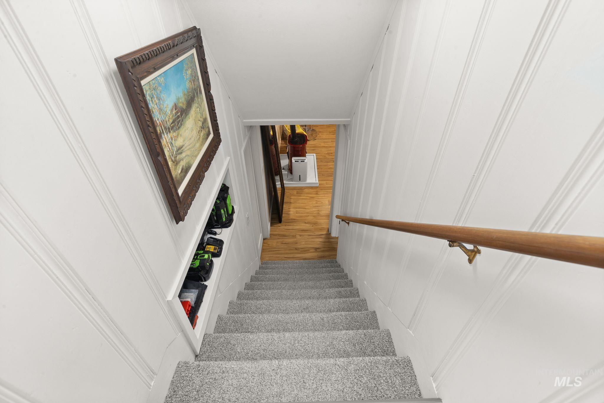 1315 8th Street Clarkston, WA 99403 - Photo 22 of 37 Carpeted staircase with white paneling and a wood handrail, leading to a lower level with wood-finish flooring