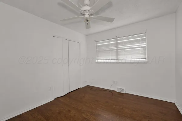 an empty room with a window and a fan
